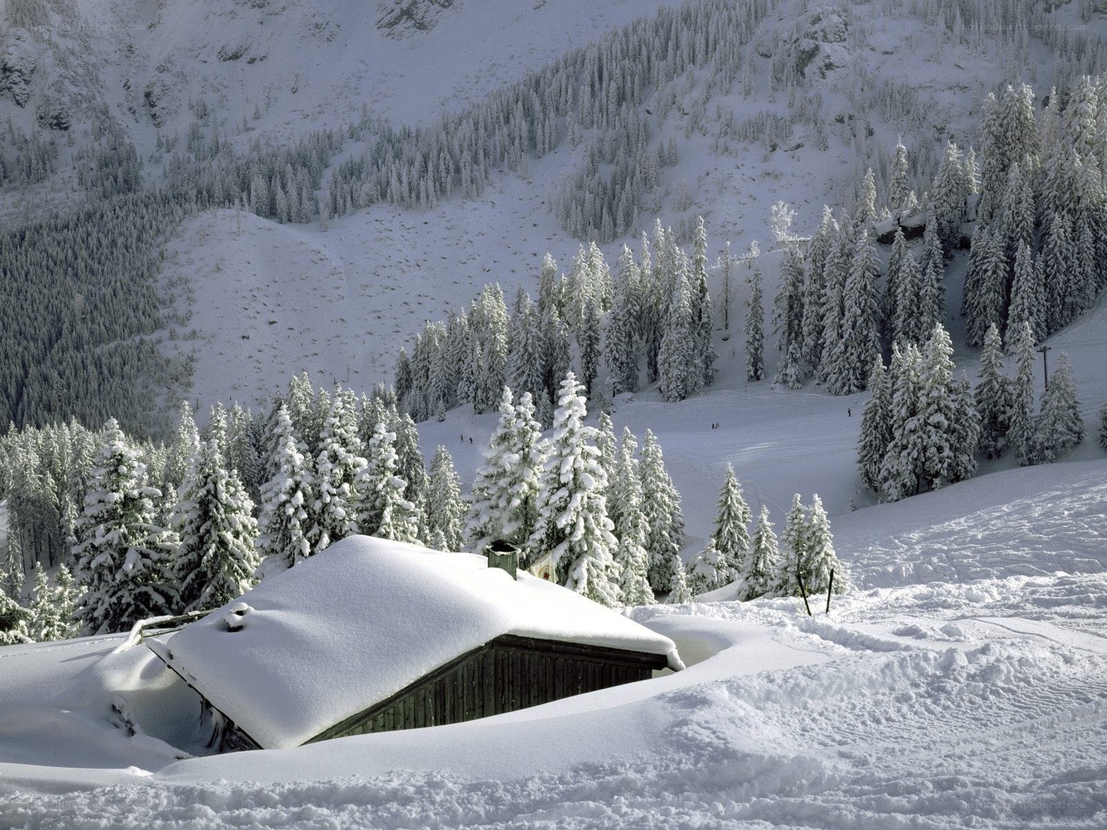 Snow-covered cabin in mountain valley