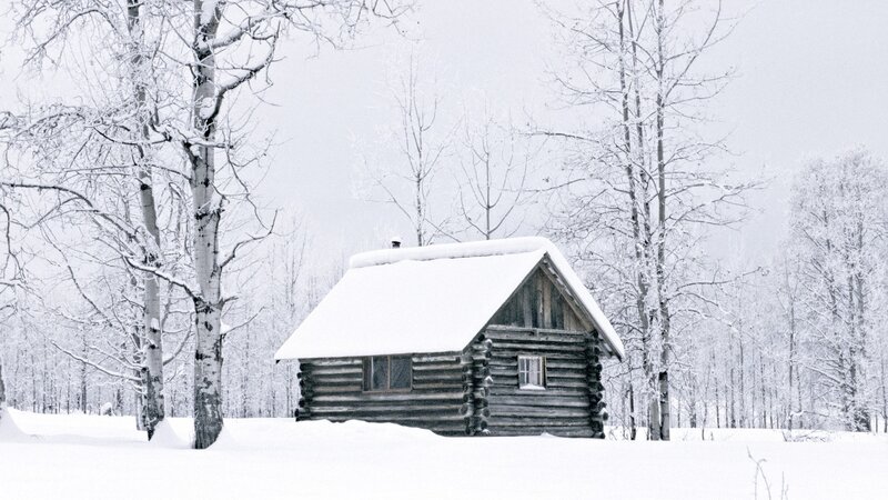 Snow-covered cabin in winter forest
