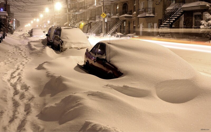 Snow-covered cars on a city street