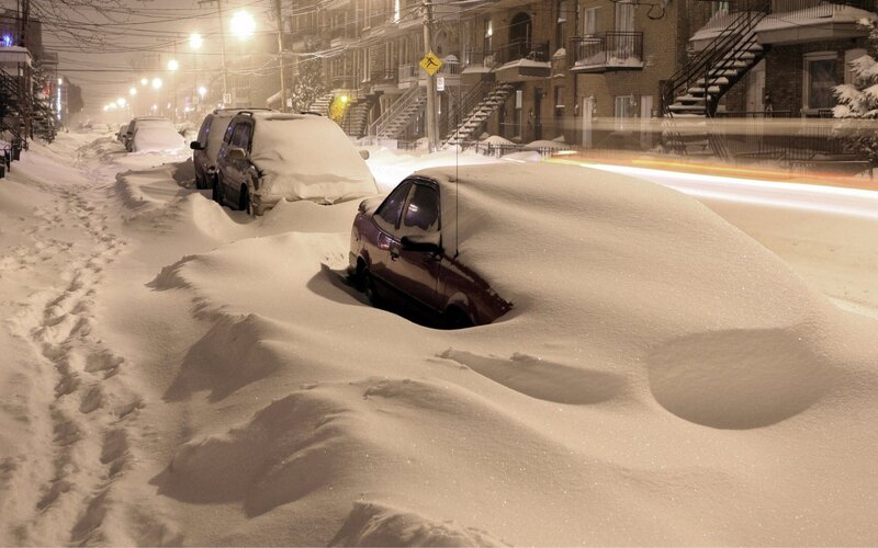 Snow-covered cars on a city street