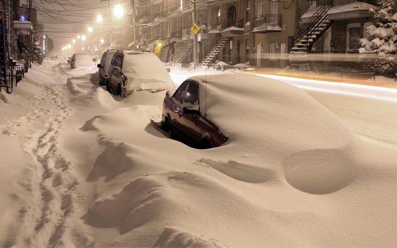 Snow-covered cars on a city street