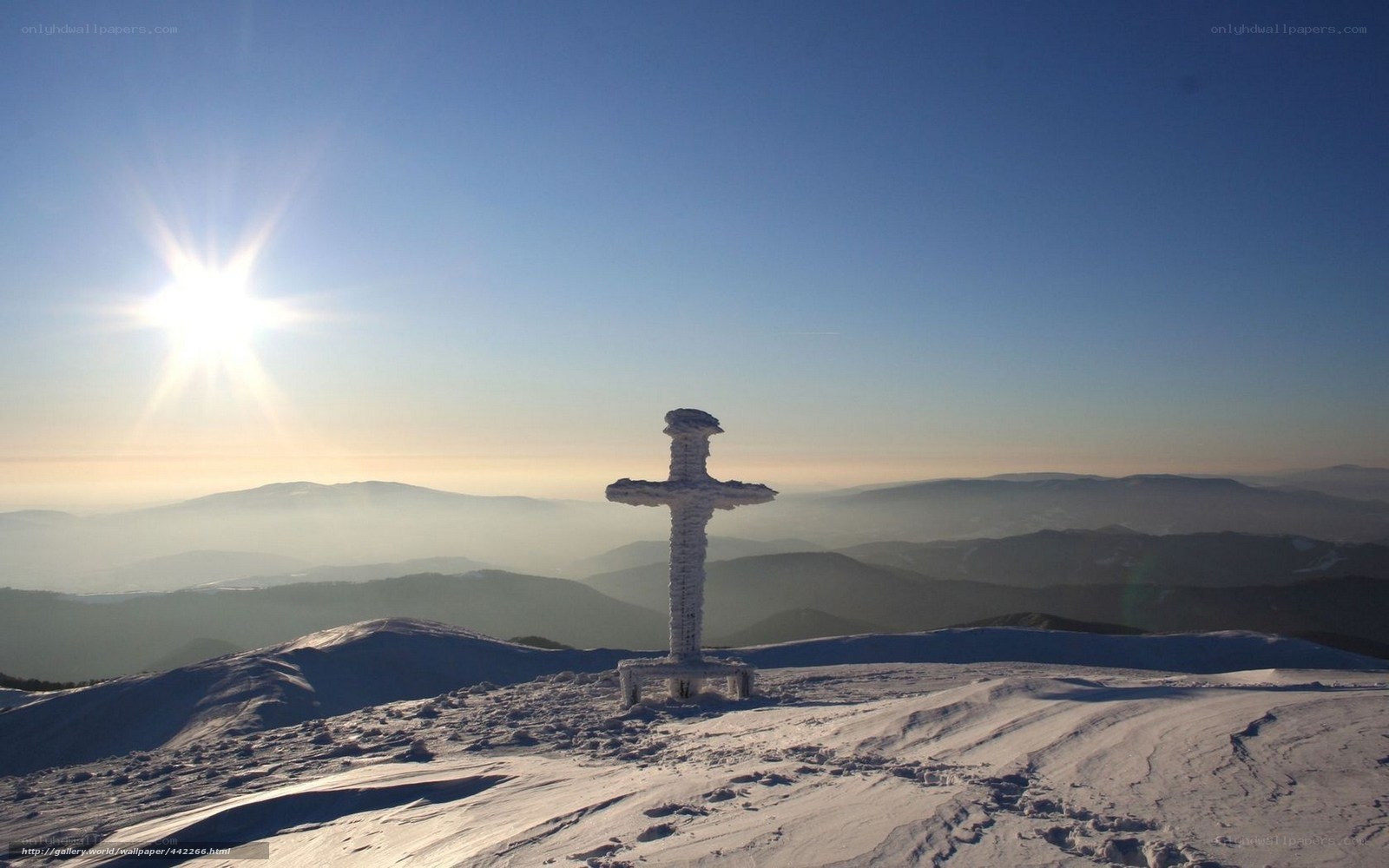 Snow-covered cross on mountain peak