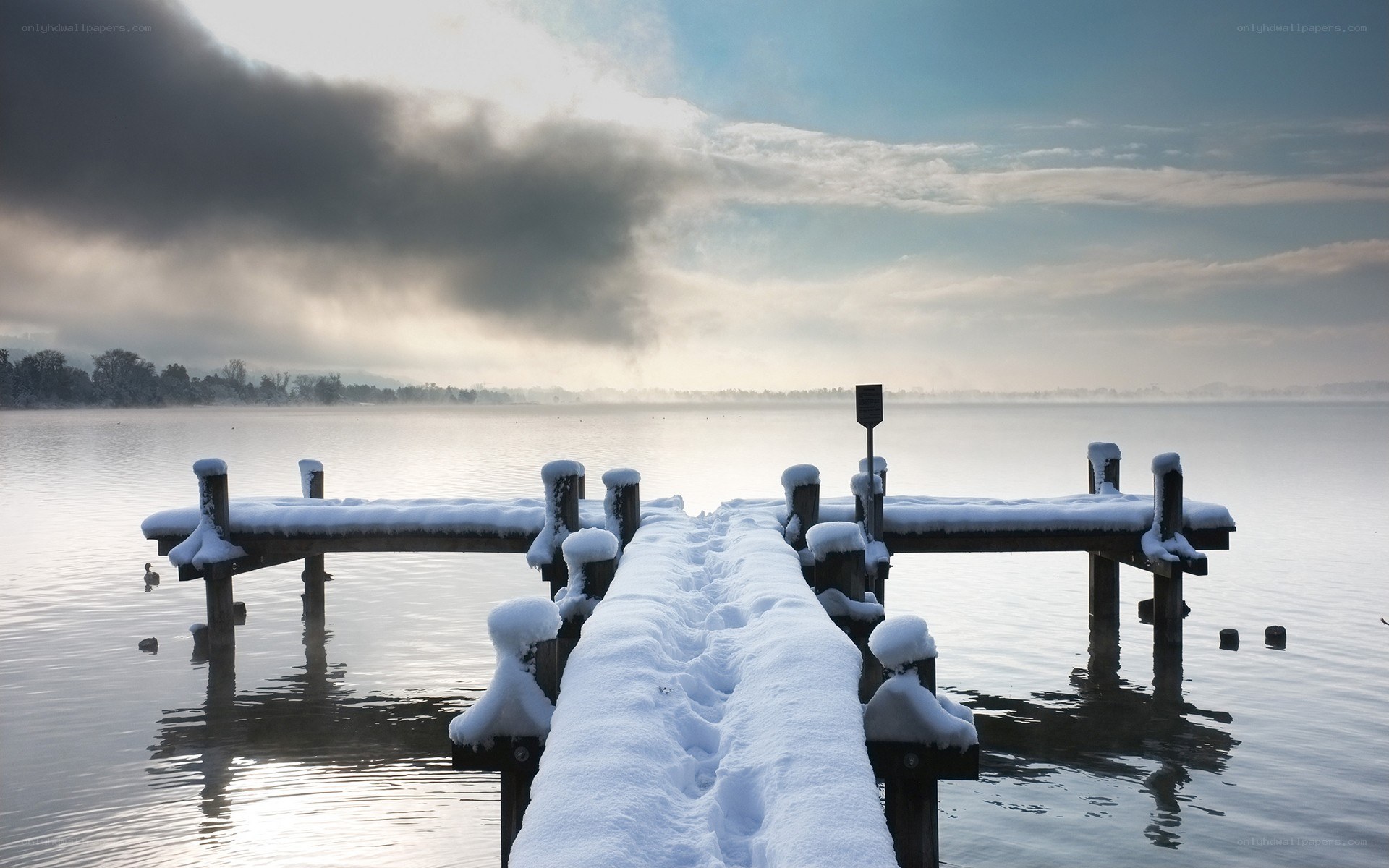 Snow-covered dock on a misty lake