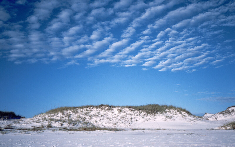Snow-covered dunes under cloudy sky
