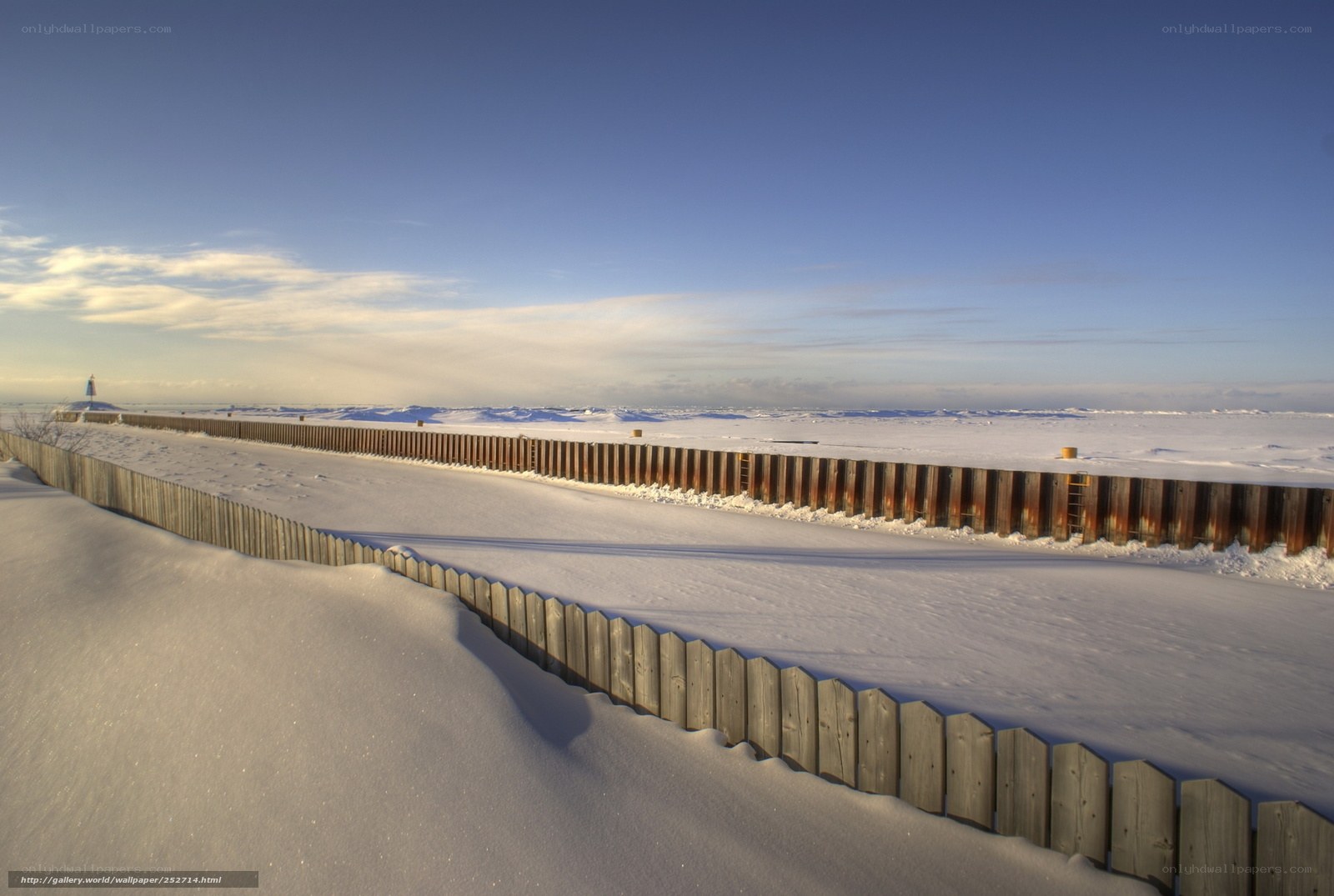 Snow-covered fence by the sea