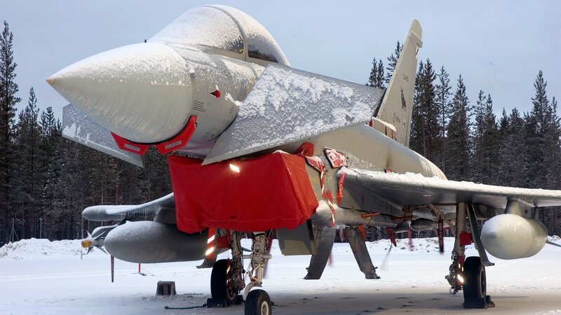 snow-covered fighter jet on tarmac