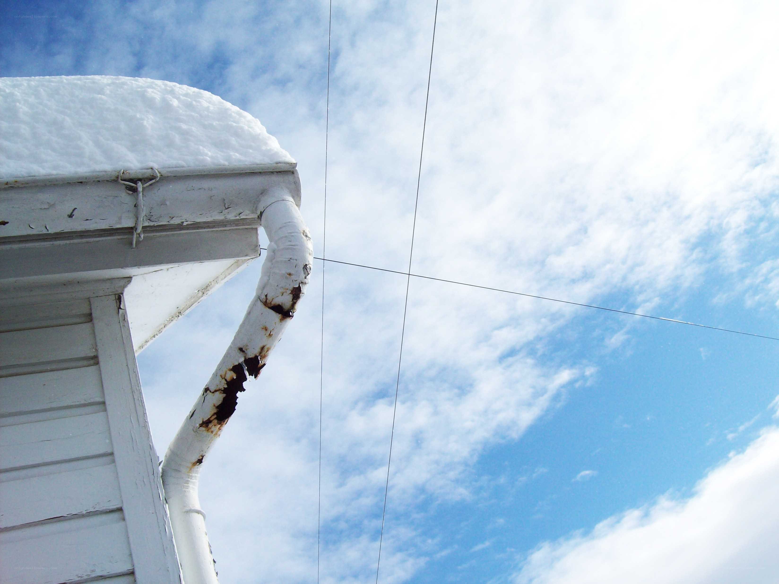 snow-covered gutter against blue sky