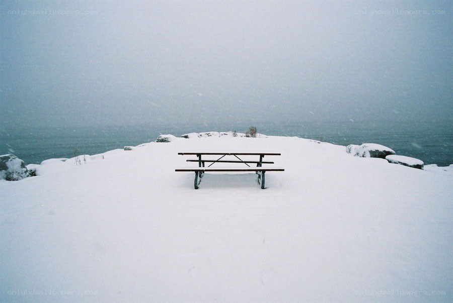 Snow-covered picnic table by the sea