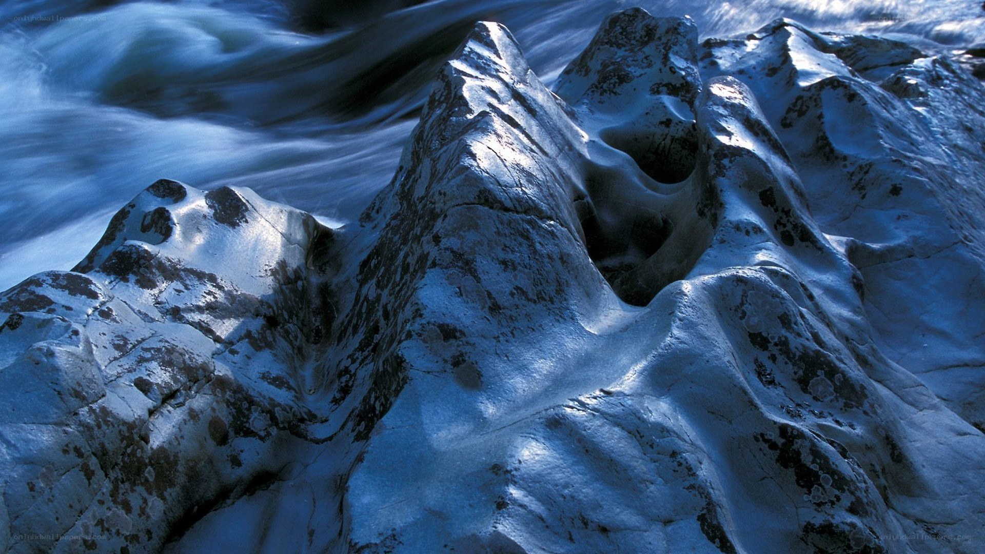 Snow-covered rocks by flowing water