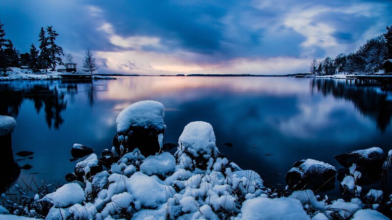 Snow-covered Rocks by Lake — Blue, Serene, Winter, Photograph, Trees, Sky