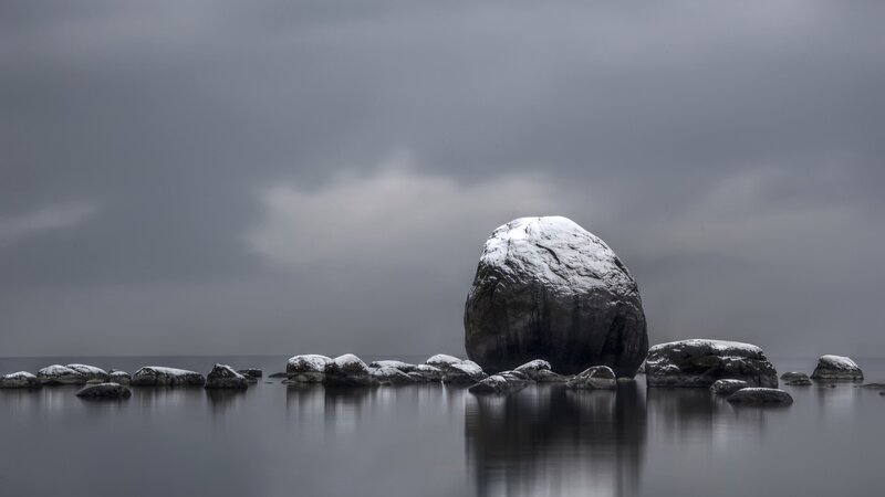 Snow-covered rocks in calm water