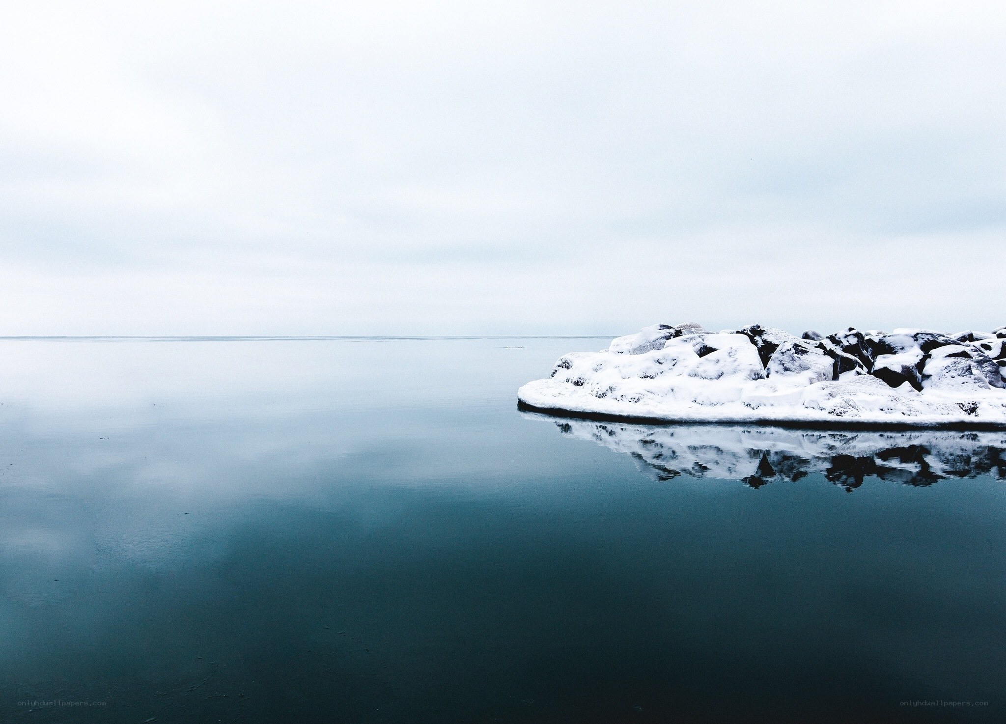 Snow-covered rocks in calm water
