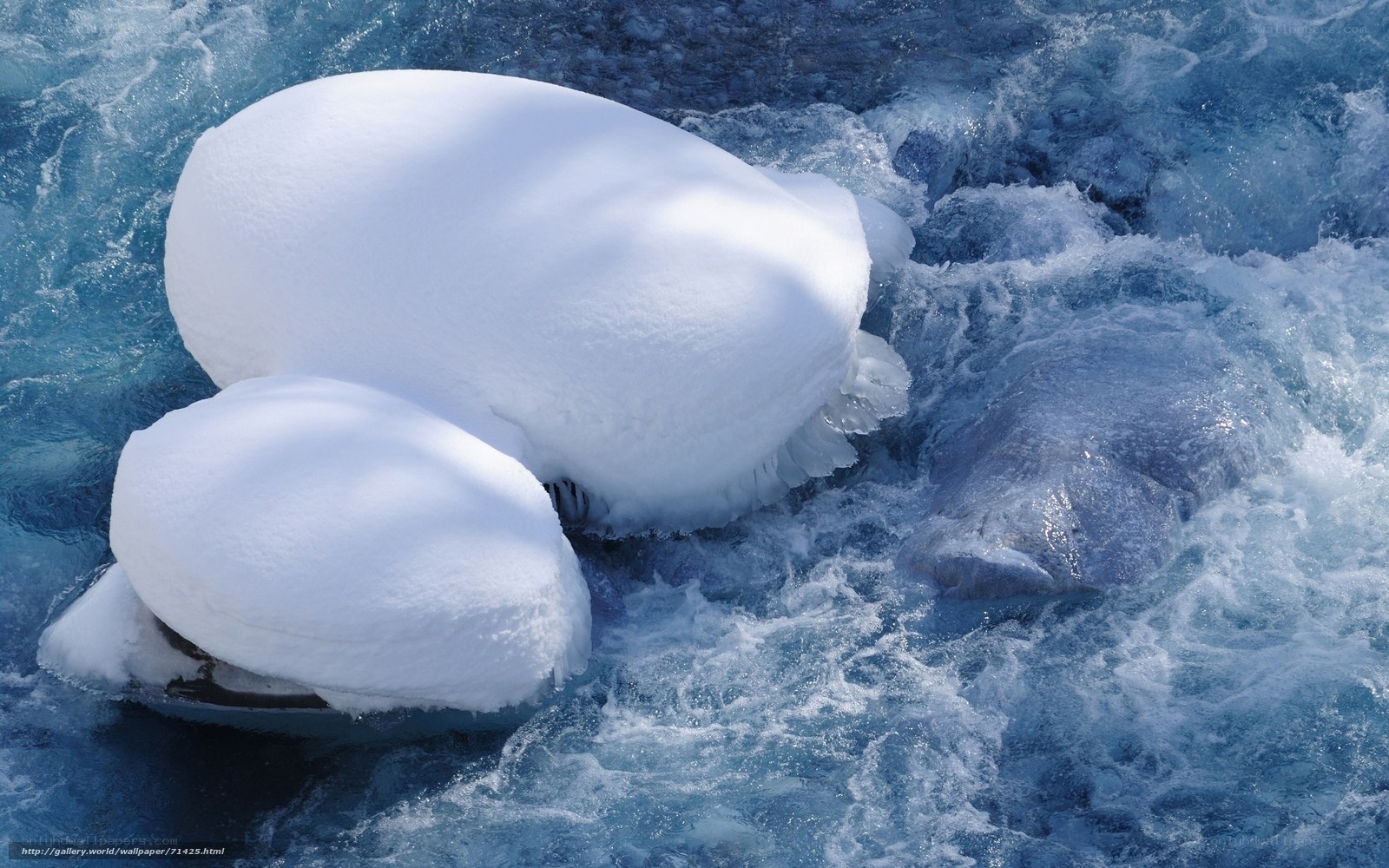 Snow-covered rocks in rushing water