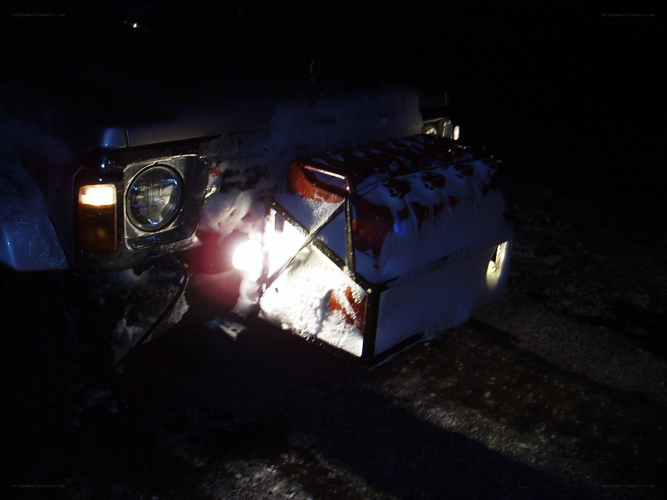 Snow-covered vehicle at night
