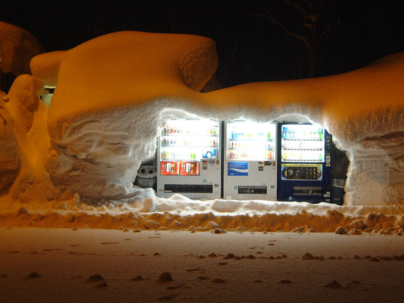 snow-covered vending machines at night