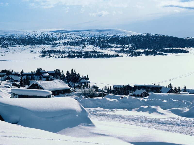 Snow-covered village by frozen lake