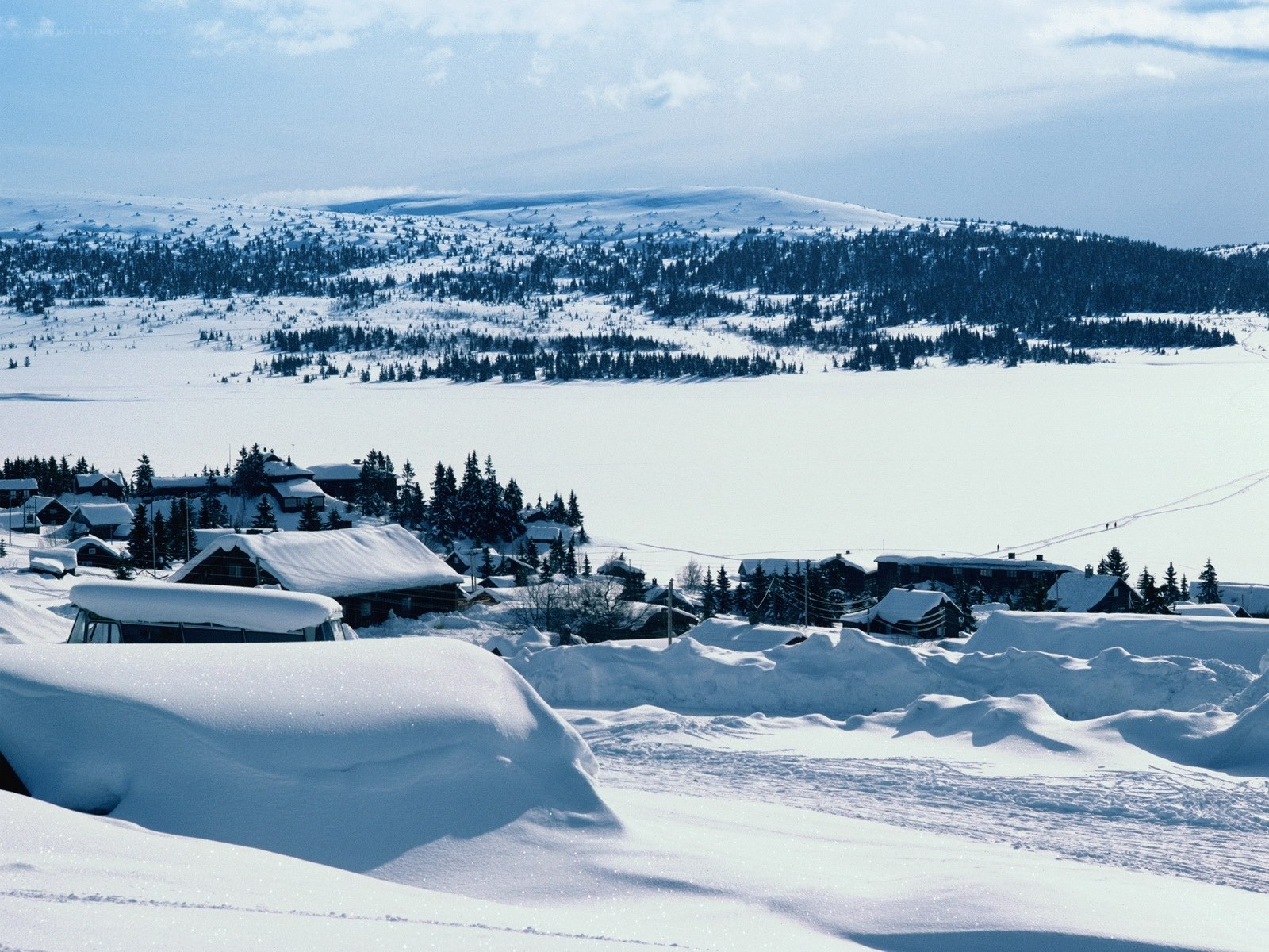Snow-covered village by frozen lake
