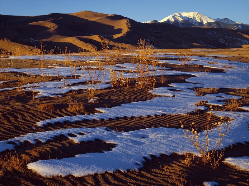 Snow-dusted dunes with mountain backdrop
