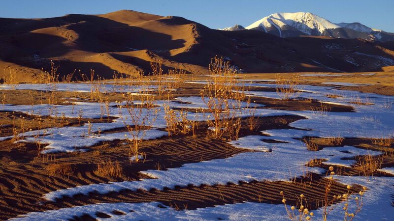 Snow-dusted dunes with mountain backdrop