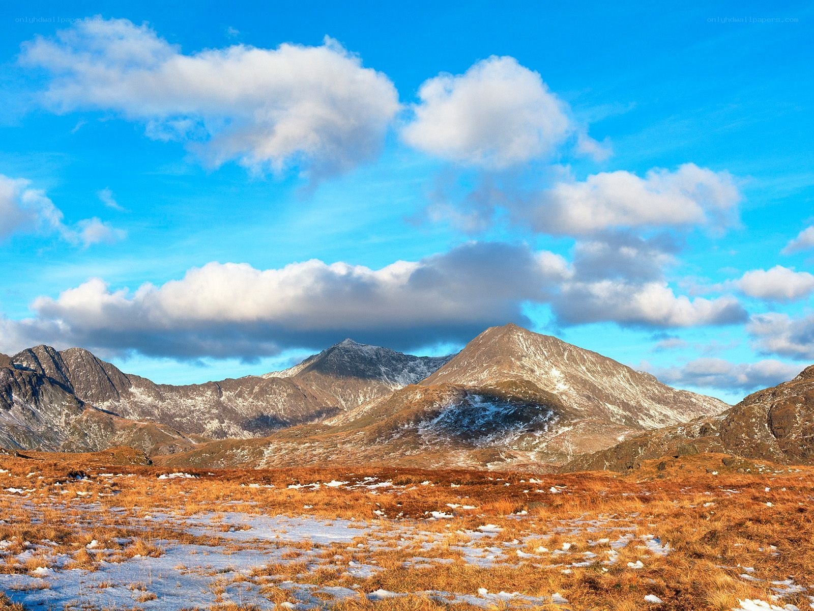 Snow-dusted mountains under blue sky