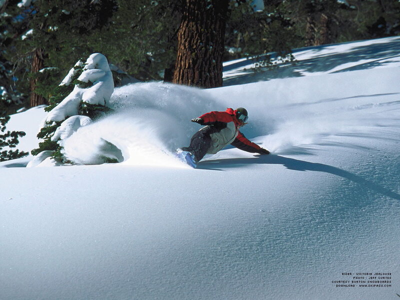 Snowboarder carving through powder
