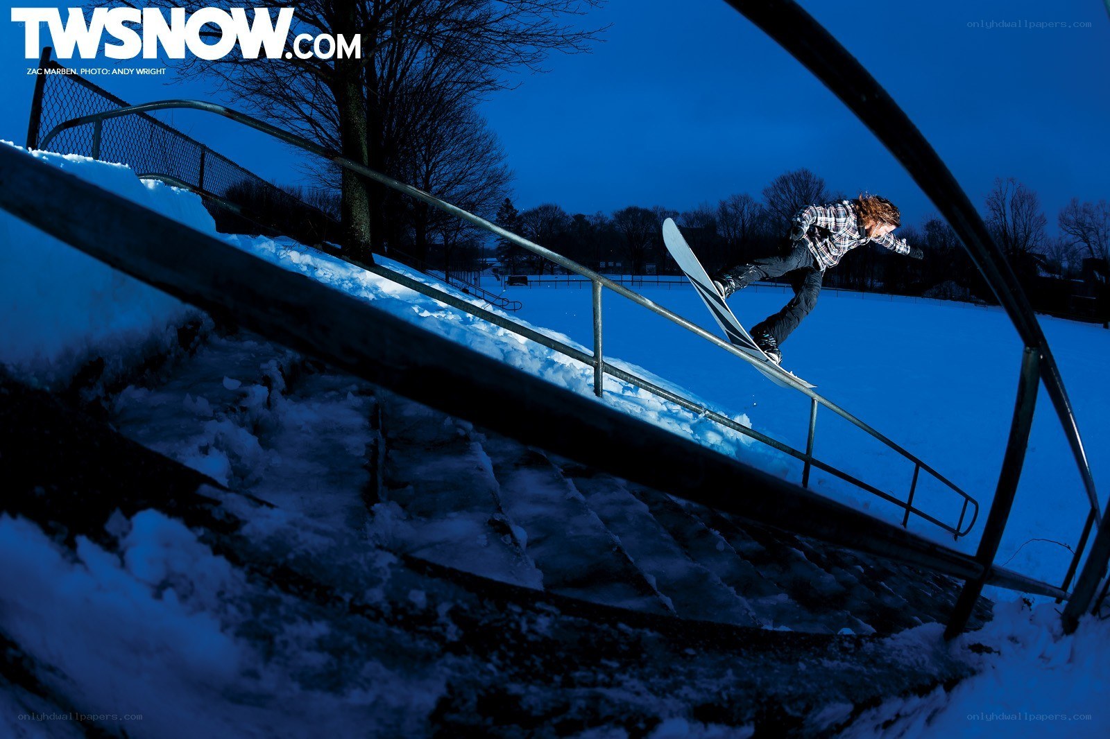 Snowboarder grinding rail at night