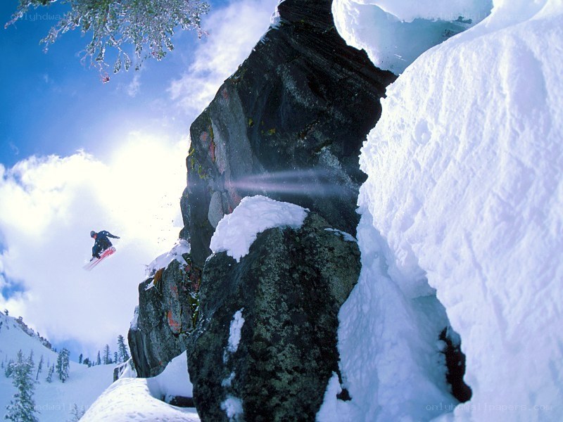 Snowboarder jumping off a rock