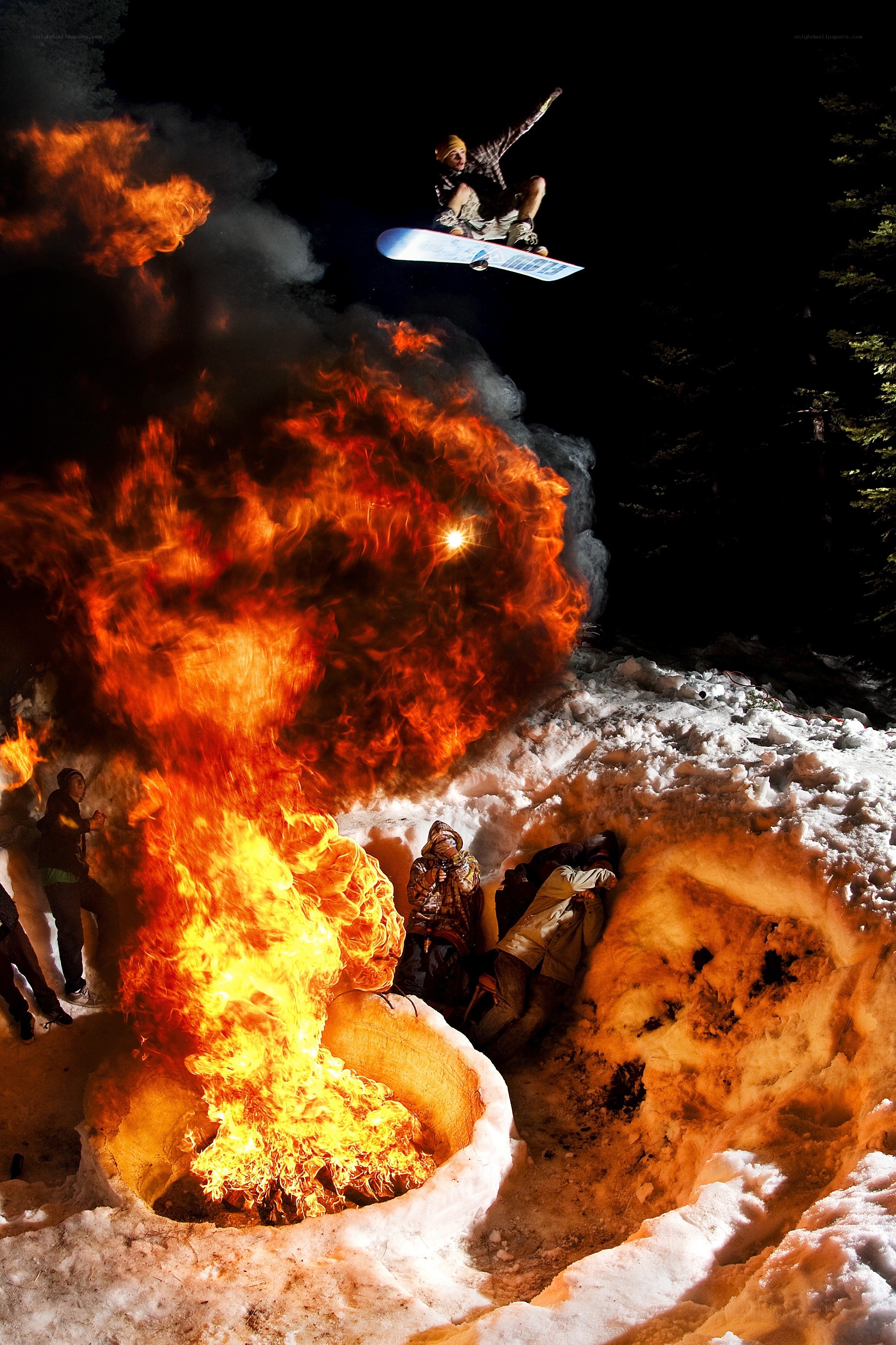 Snowboarder jumps over fire
