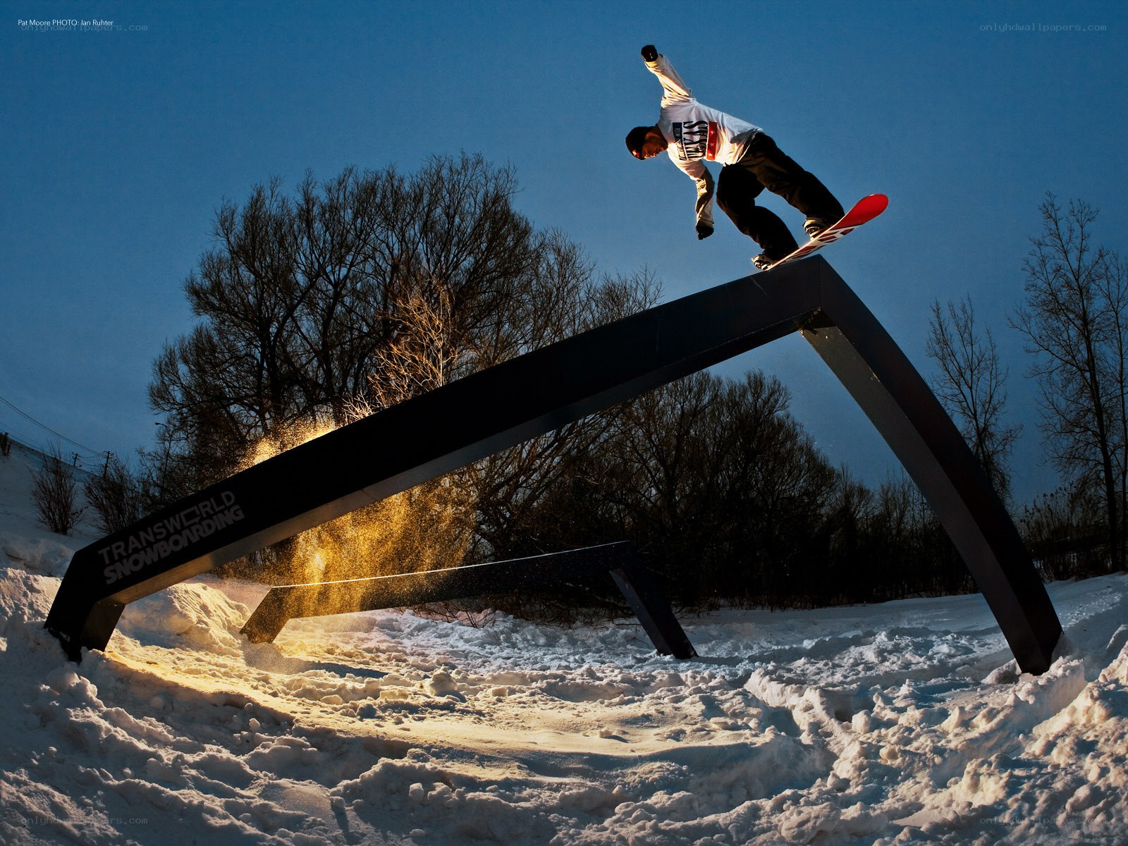 Snowboarder on rail at dusk