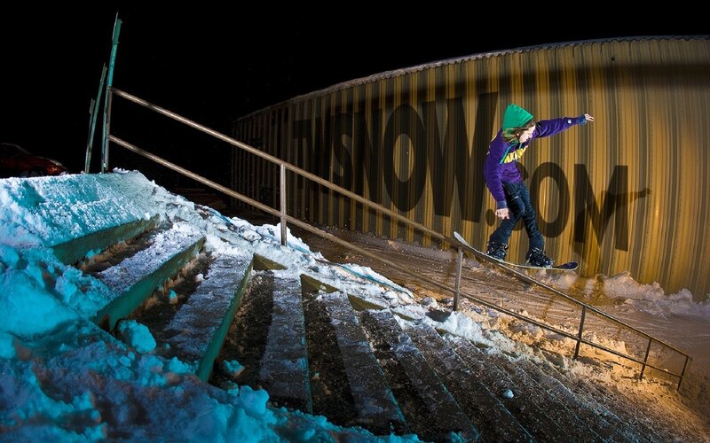 Snowboarder on rail at night