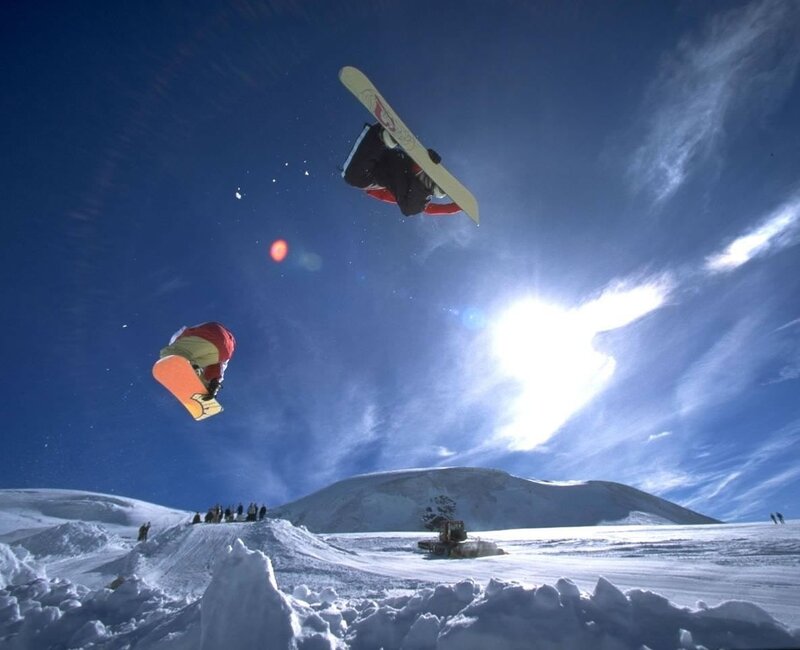 Snowboarders in mid-air jump