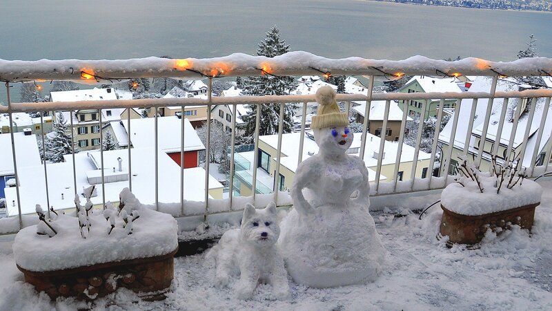 Snowman and dog on snowy balcony