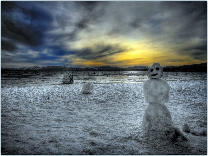 Snowman on frozen lake at sunset