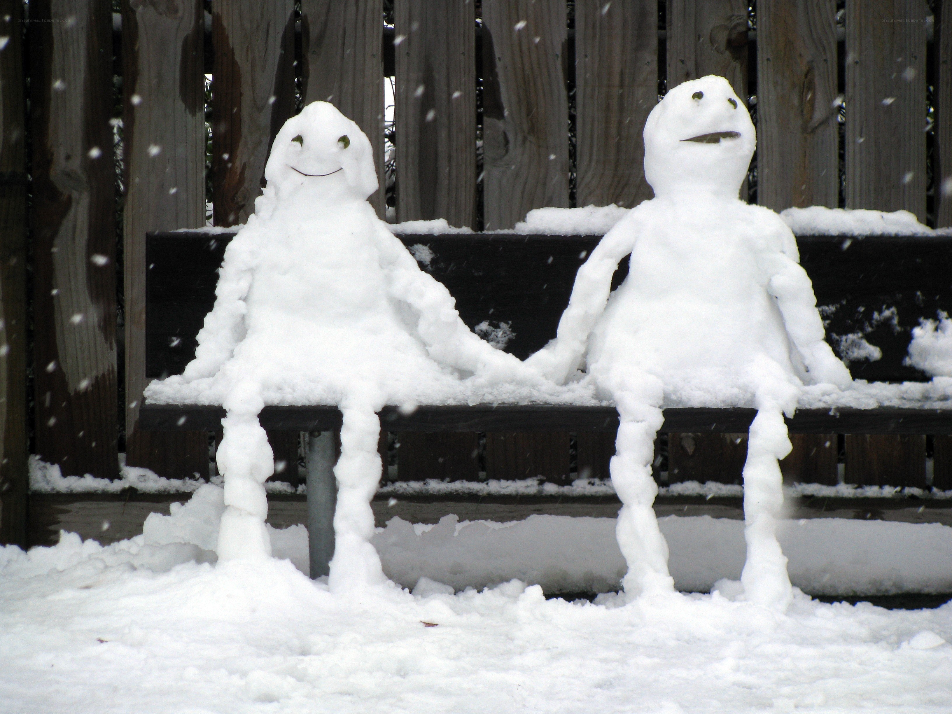 Snowmen holding hands on bench