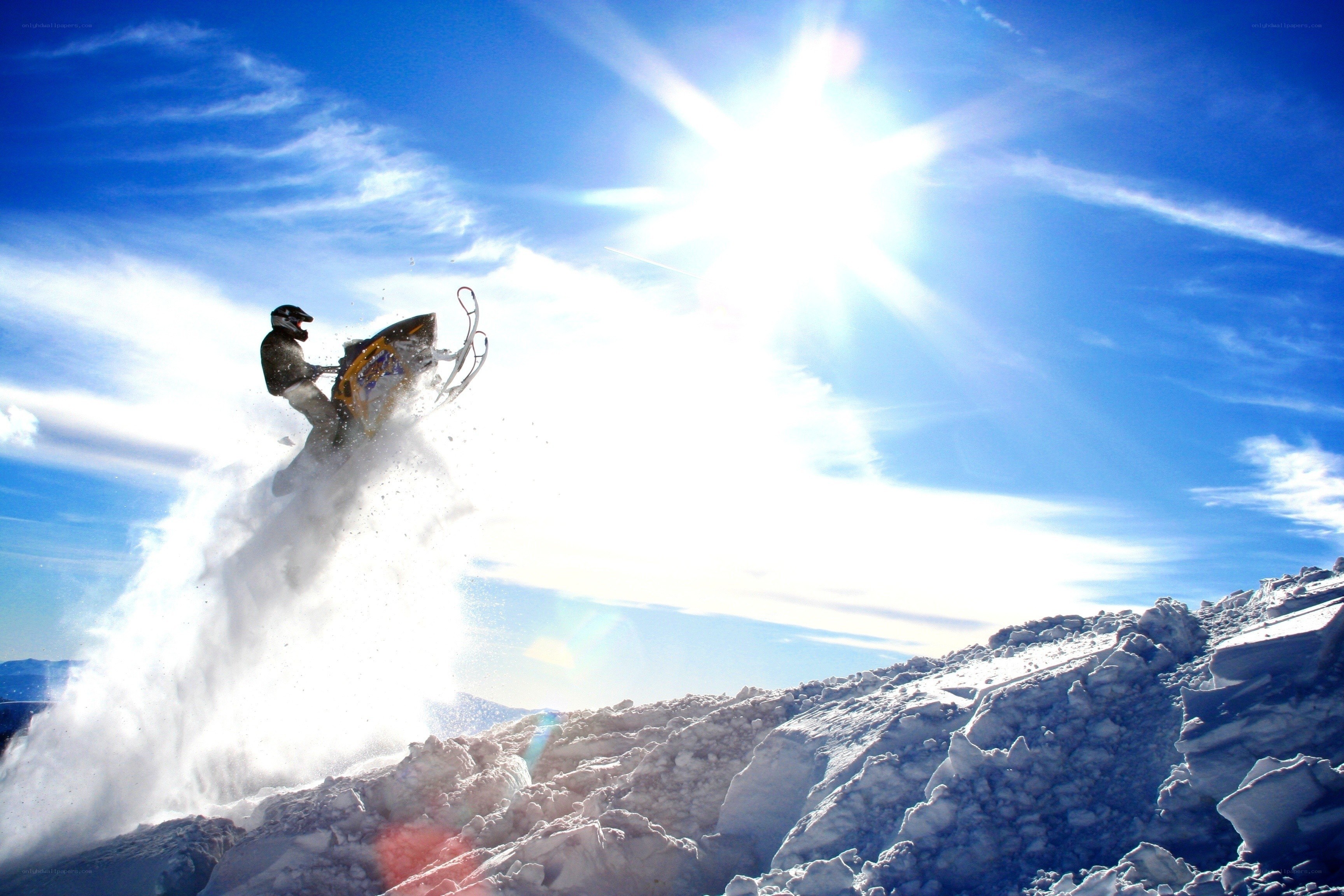 Snowmobiler jumps in bright sun