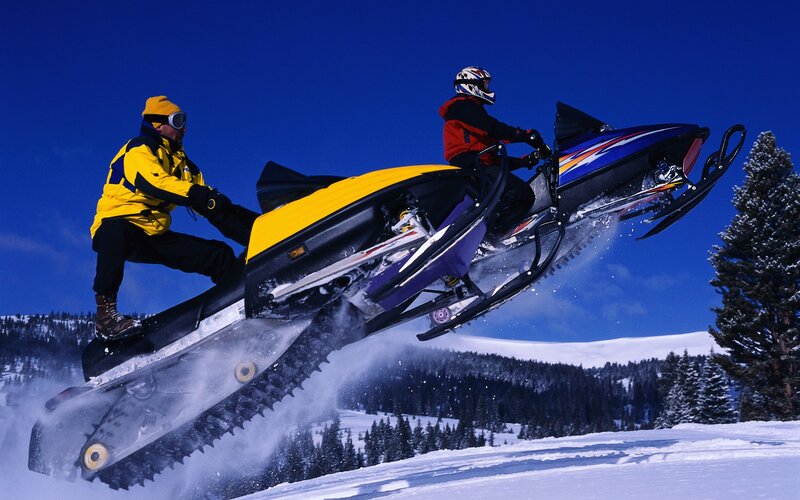 Snowmobilers in mid-air jump