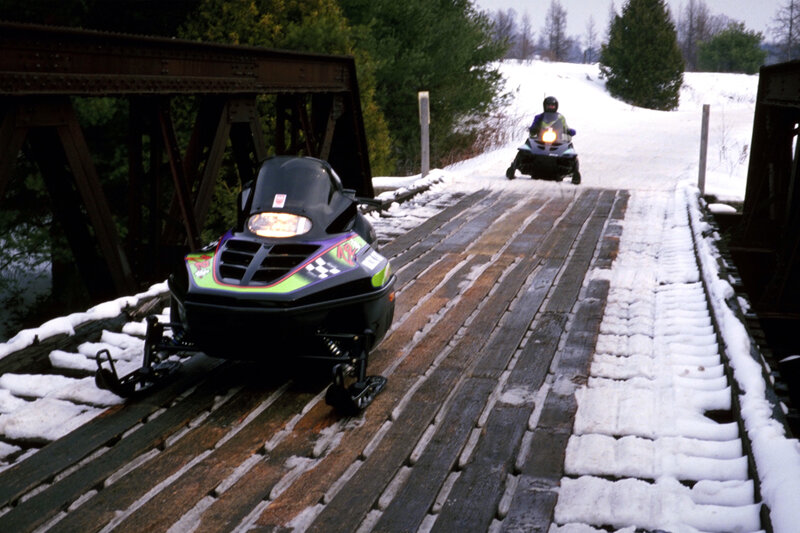 Snowmobiles on a snowy bridge