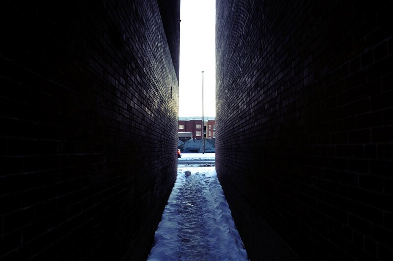 Snowy alley between brick walls