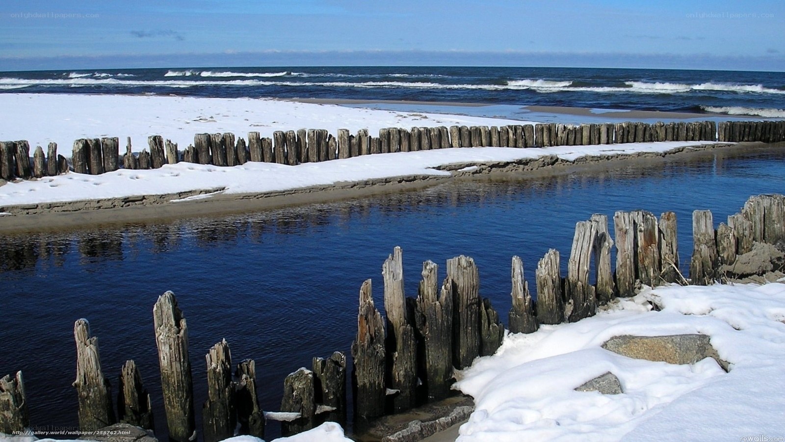 Snowy beach with wooden posts