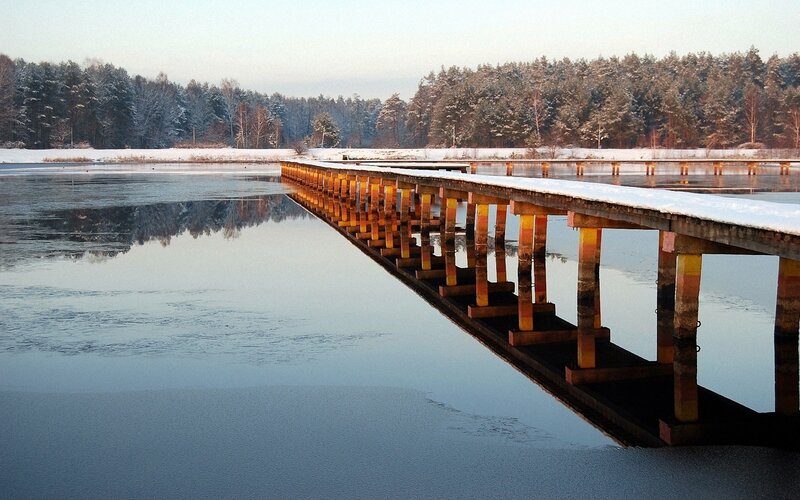Snowy bridge over calm lake