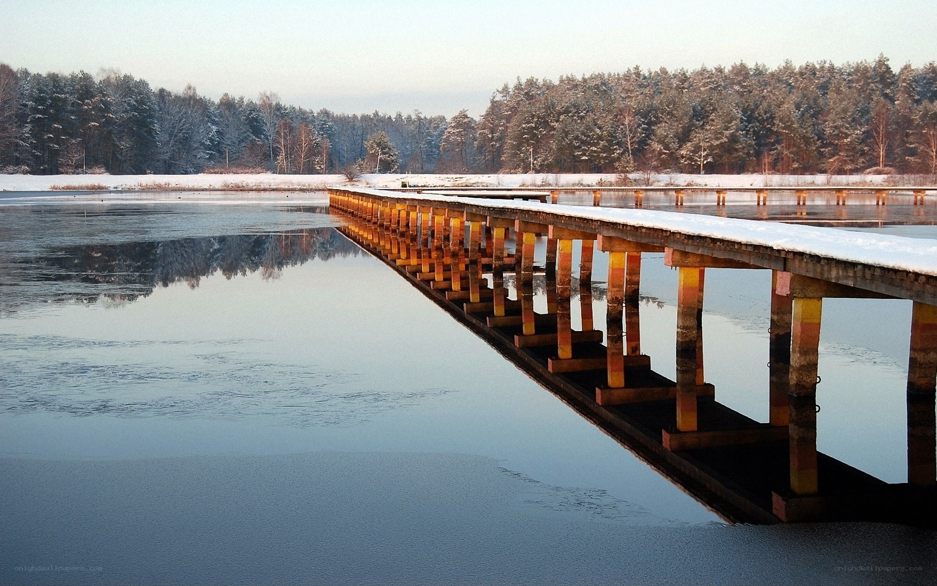Snowy bridge over calm lake