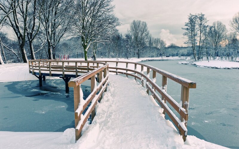 Snowy bridge over frozen pond