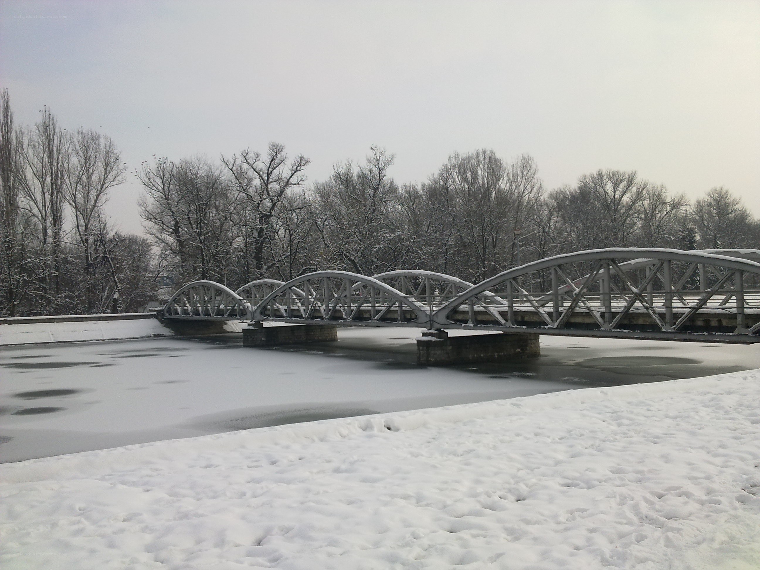 Snowy bridge over frozen river