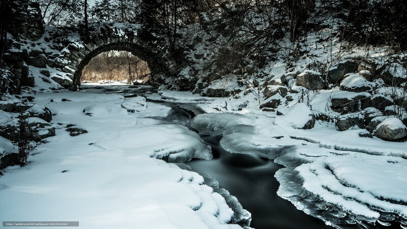 Snowy bridge over frozen stream