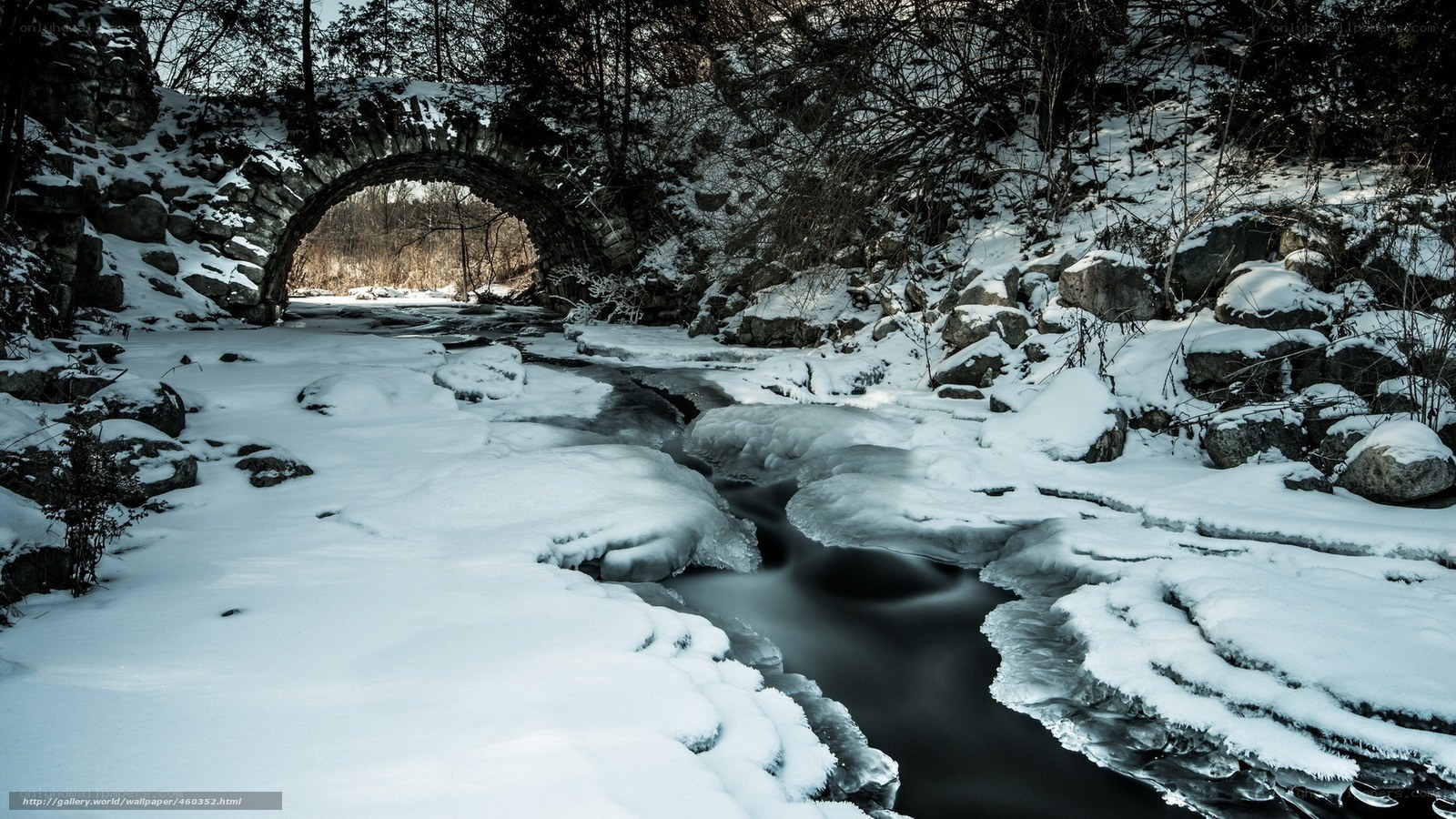Snowy bridge over frozen stream