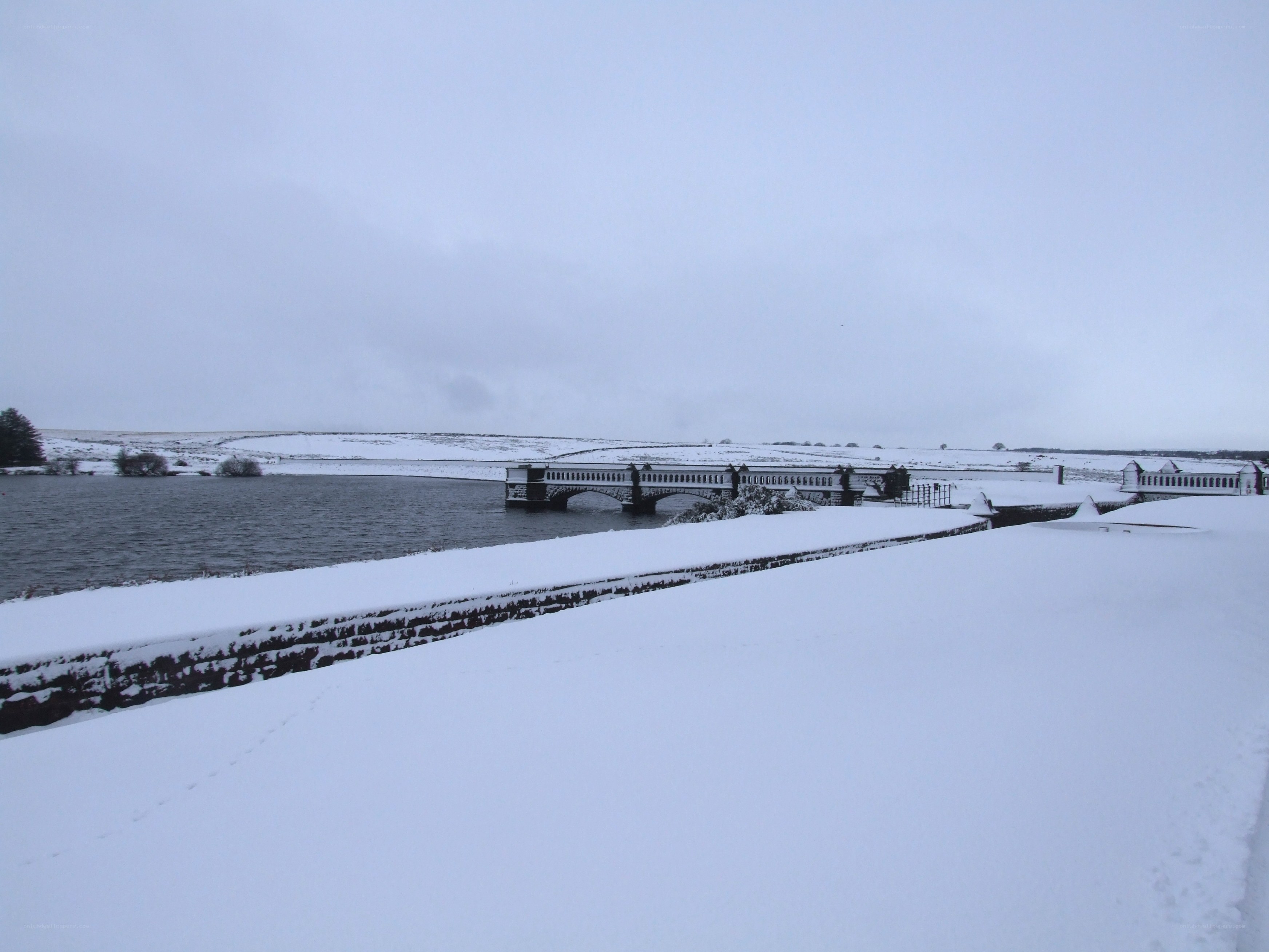 Snowy bridge over reservoir