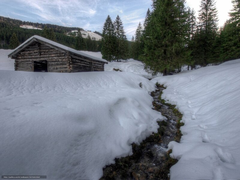 Snowy cabin by a stream