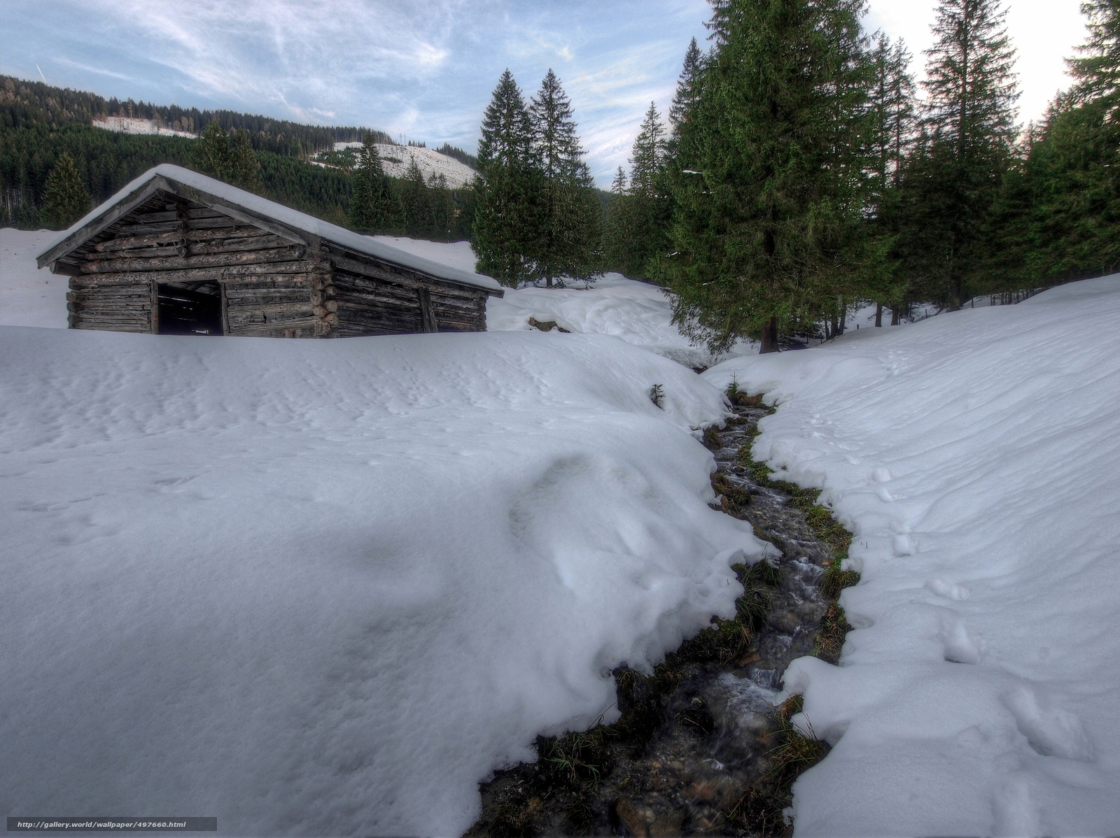 Snowy cabin by a stream