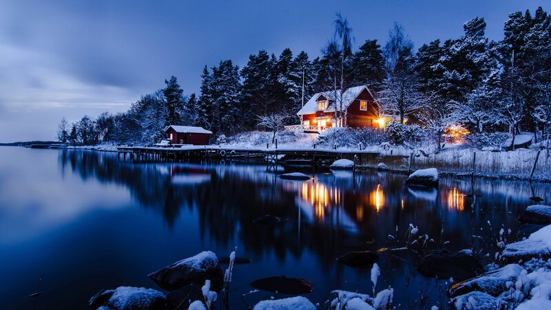 Snowy cabin by the lake at dusk