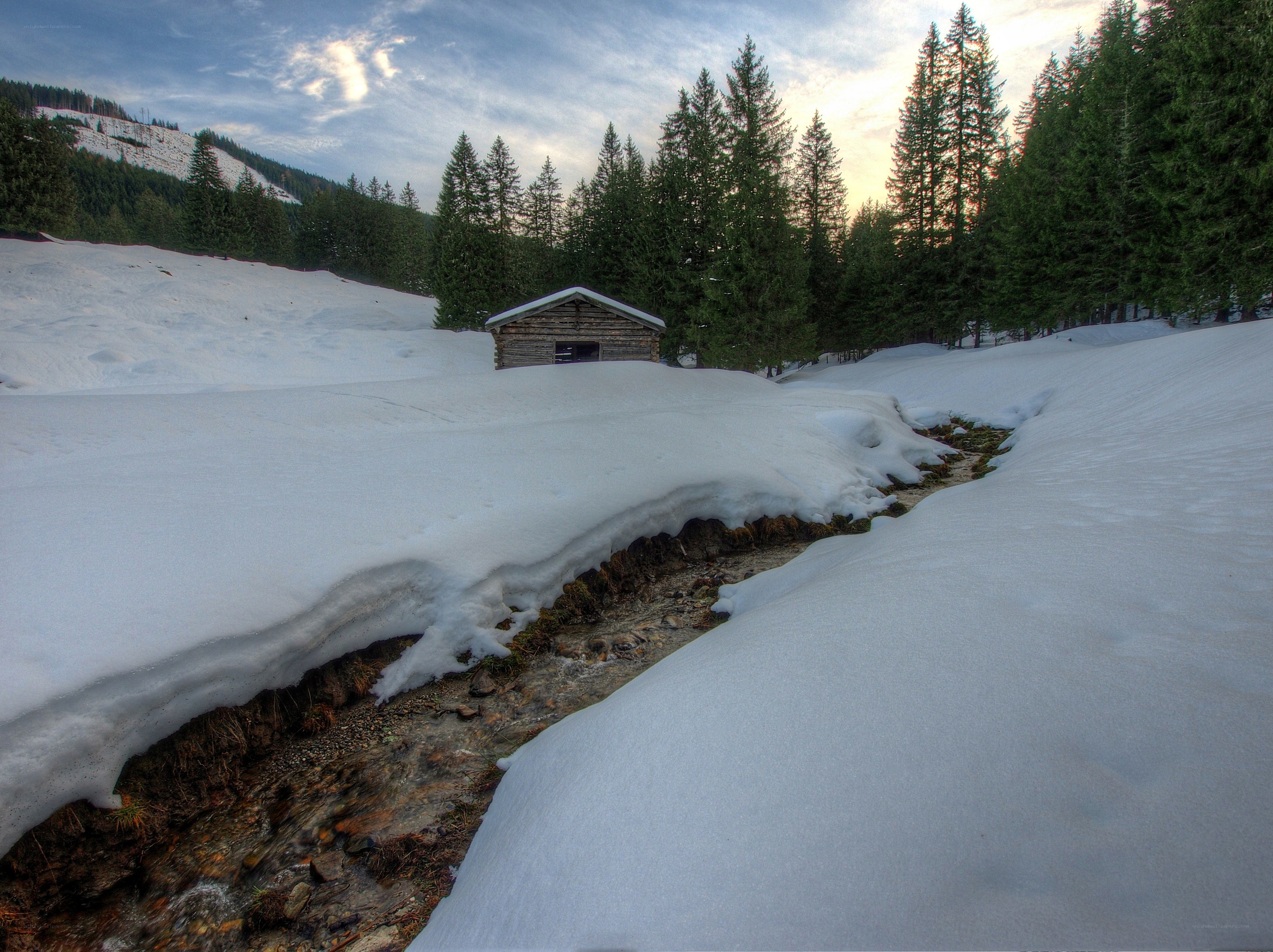 Snowy cabin in forest valley